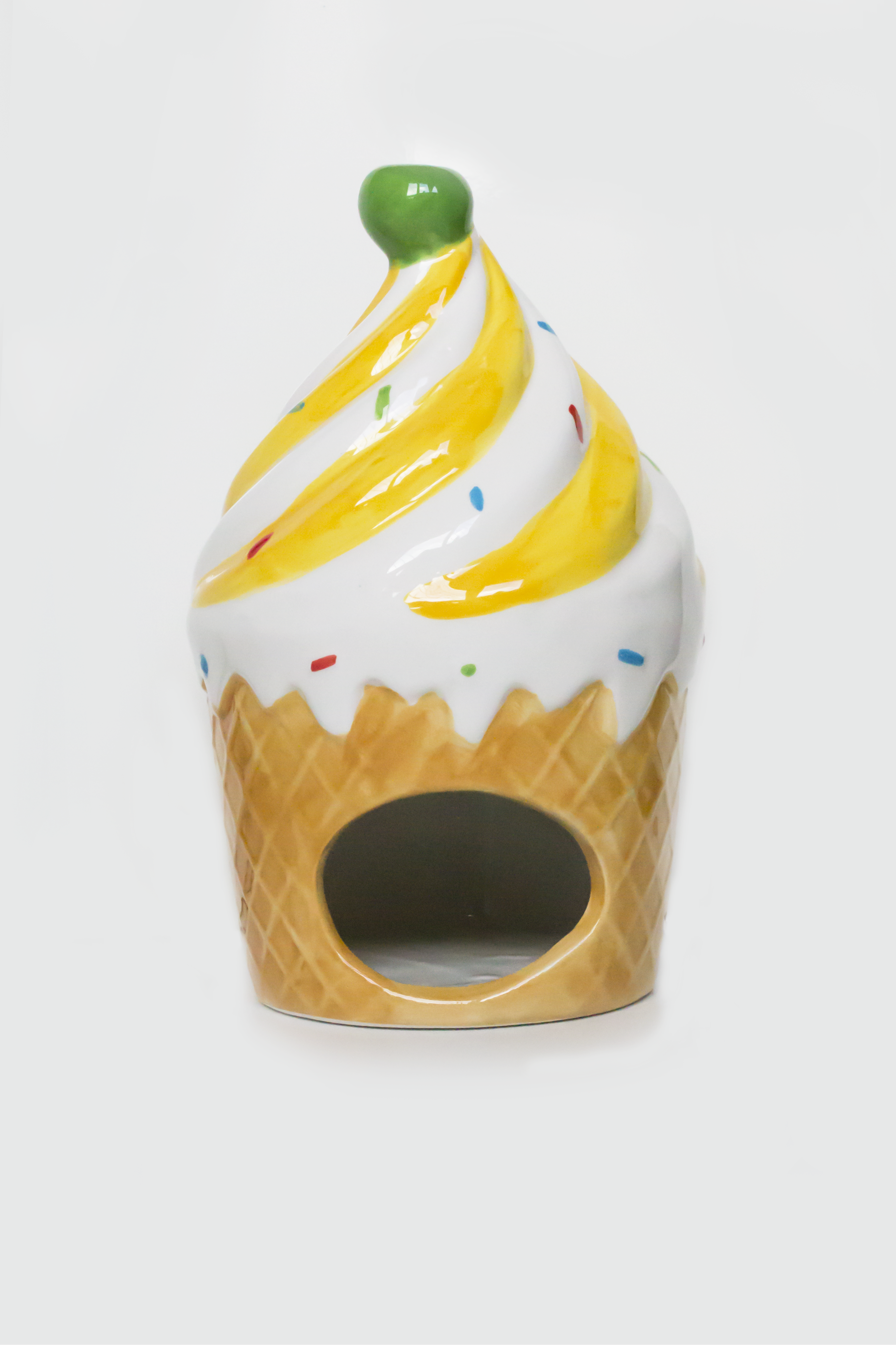 Ceramic ice cream cone-shaped container with yellow swirl and green top on a white background