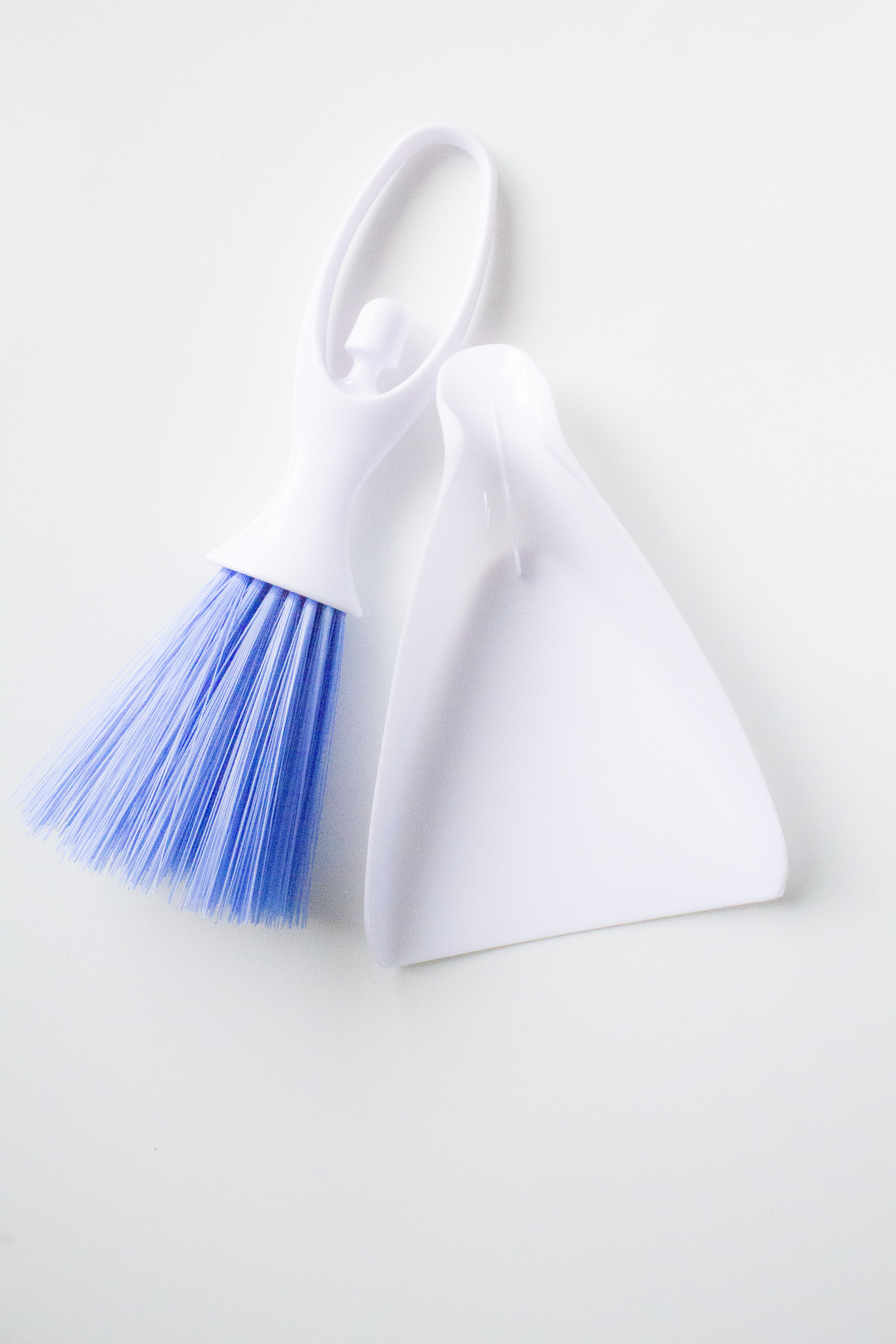 White dustpan with blue bristle brush on a white background