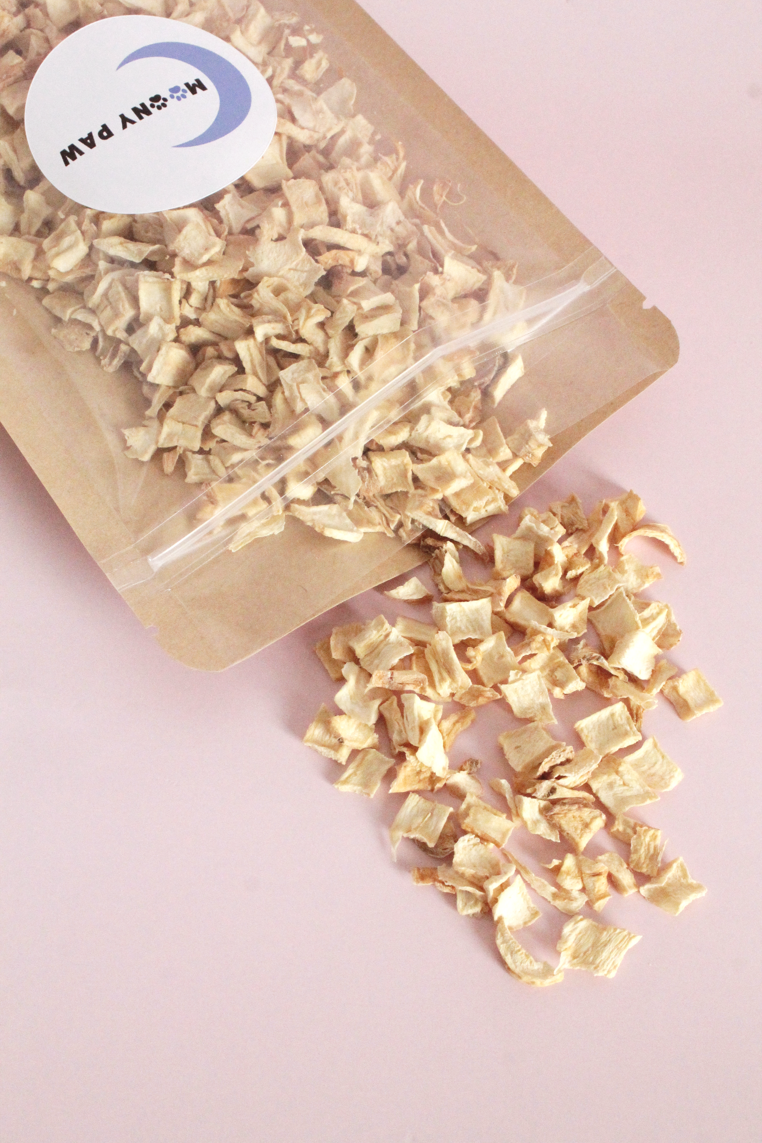 Clear bag with gold-colored square pieces spilling out on a pink background, branded &