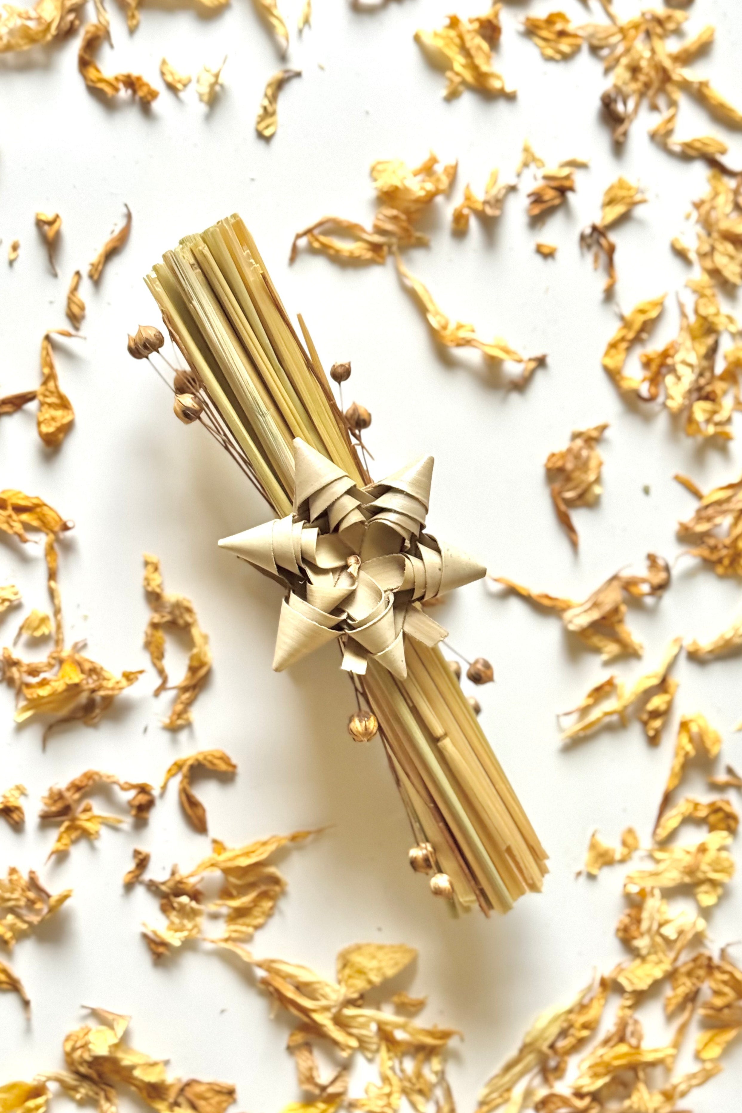 Gold decorative item with tassels on a white background with gold leaves.