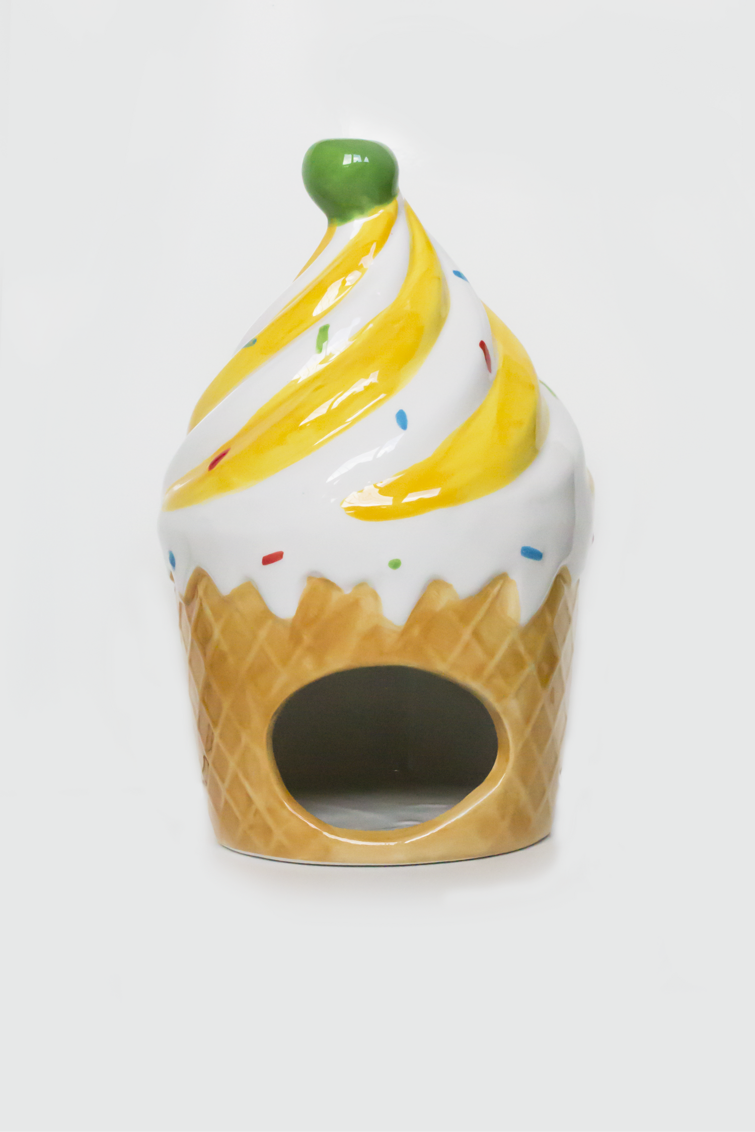 Ceramic ice cream cone-shaped container with yellow swirl and green top on a white background