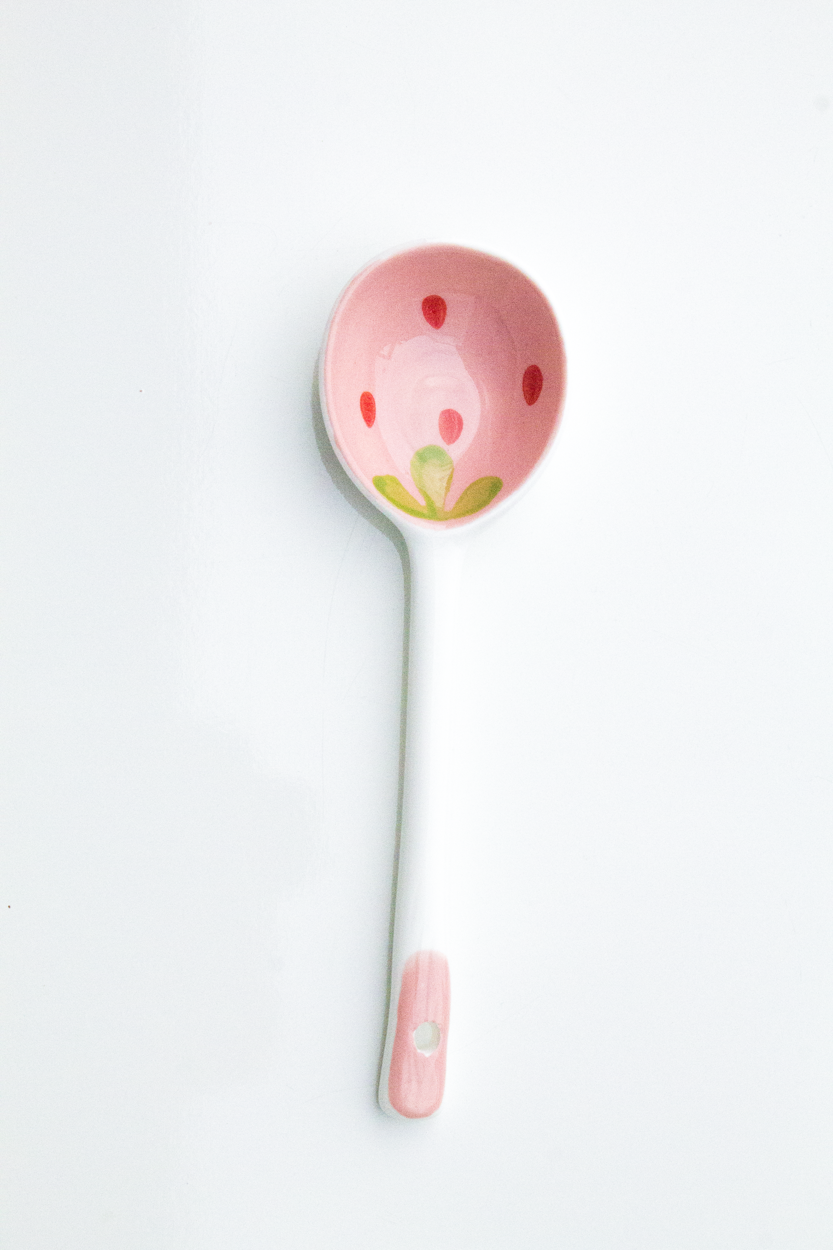Pink spoon with floral design on a light gray background