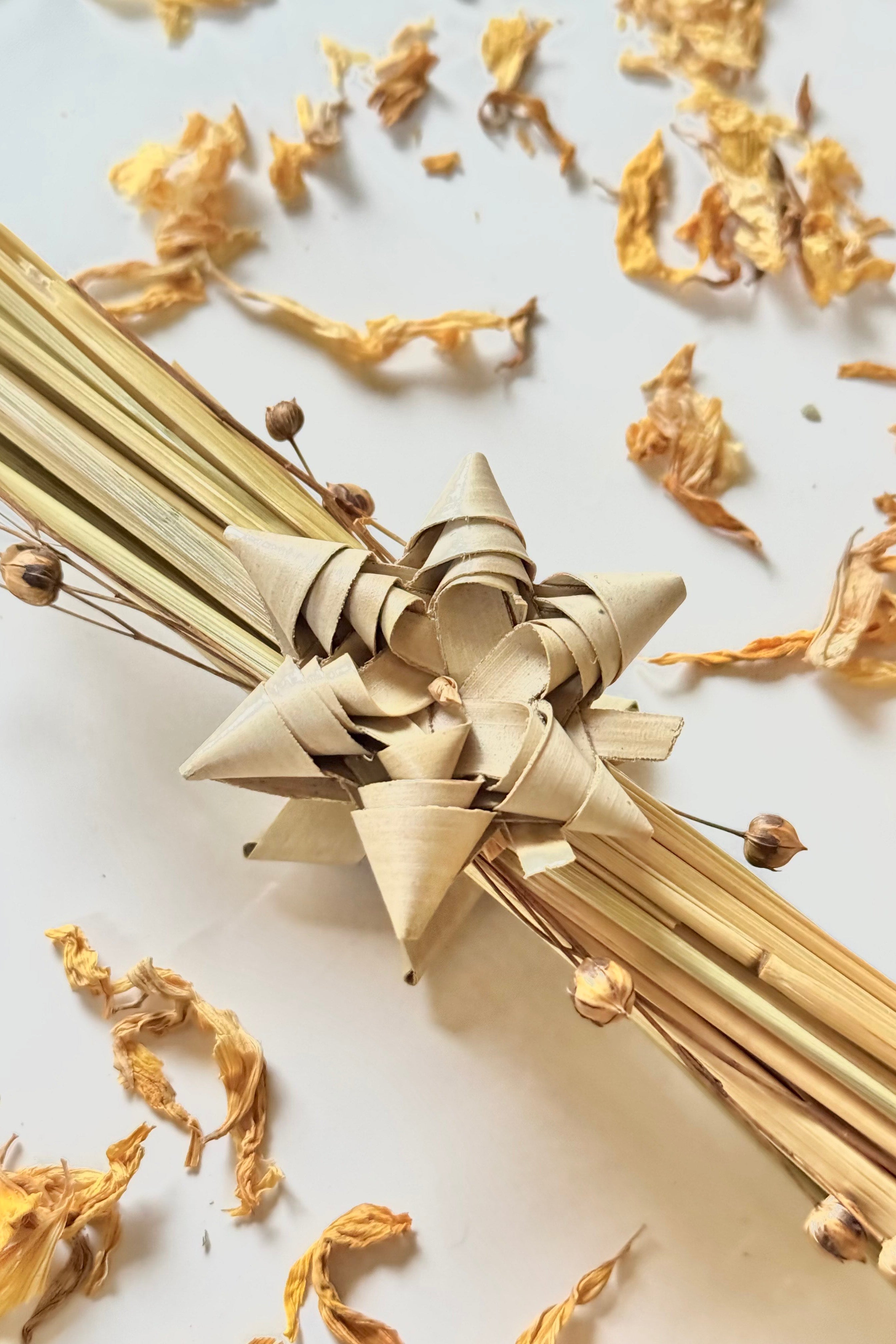 Decorative chew made of dried grasses on a light background with scattered dried flowers.