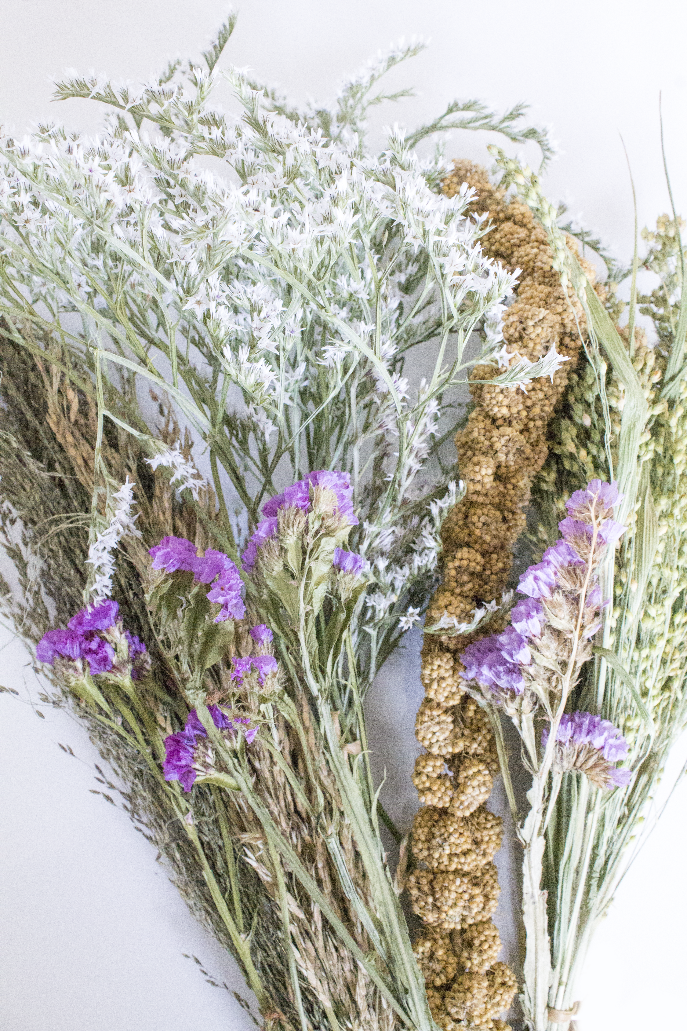 Bouquet of dried flowers with purple blooms and greenery on a light background